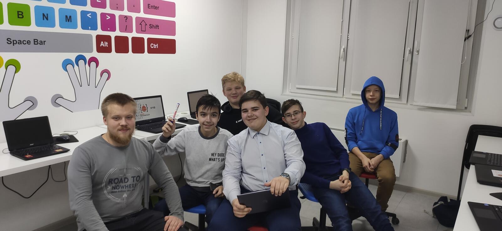 Группа подростков в IT-лагере улыбаются и общаются друг с другом