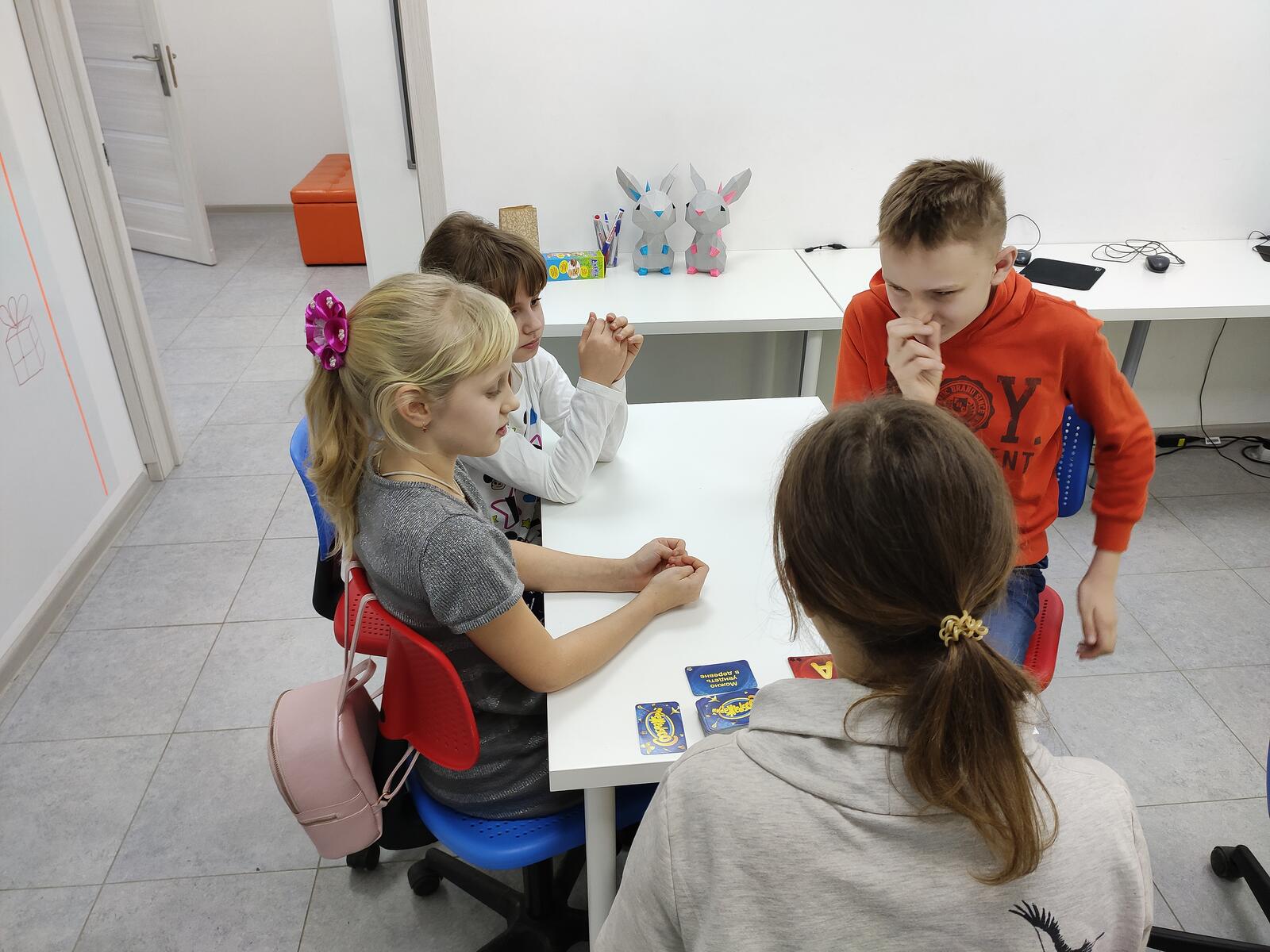 Группа детей за столом играют в настольную игру — лагерь даёт среду для роста уверенности